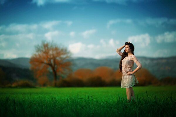 Ragazza in abito sullo sfondo di un bellissimo albero autunnale e un enorme campo