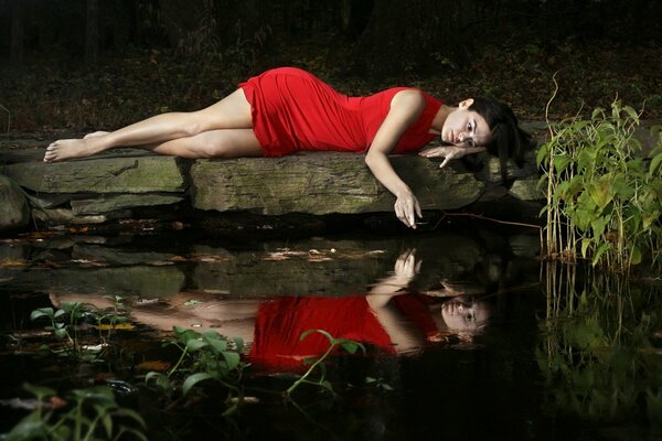 La chica de rojo en la piedra del lago está triste