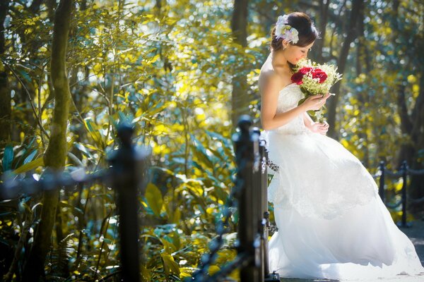 An Asian woman in a bride s dress holds a bouquet