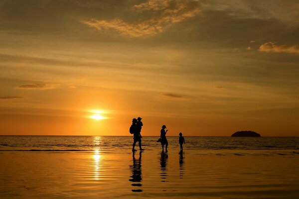 Les silhouettes de la famille sur fond de coucher du soleil et de la mer