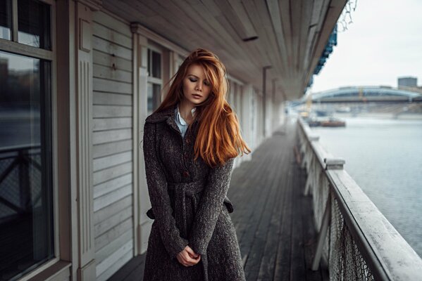 Sur la rive derrière la clôture se trouve une fille aux cheveux roux