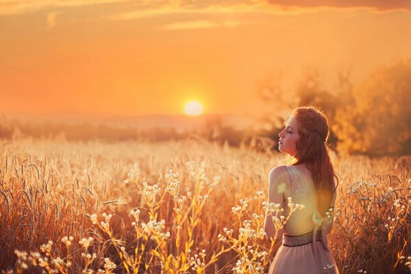 Fille rousse au fond du soleil dans le champ