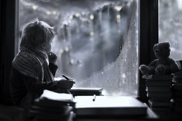 The boy looks out the window winter