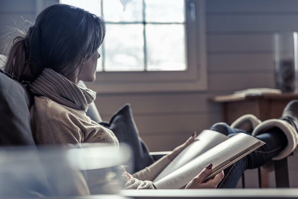 La jeune fille est assise dans une chaise et lit un magazine