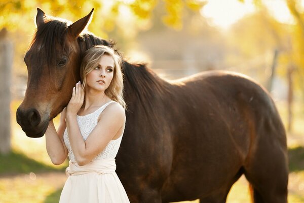 Fille en robe blanche caresse un cheval