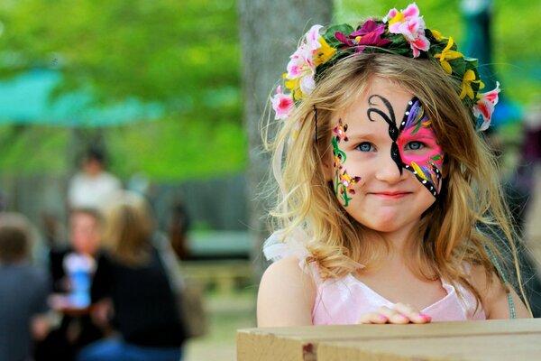 A girl with a painted face in a wreath