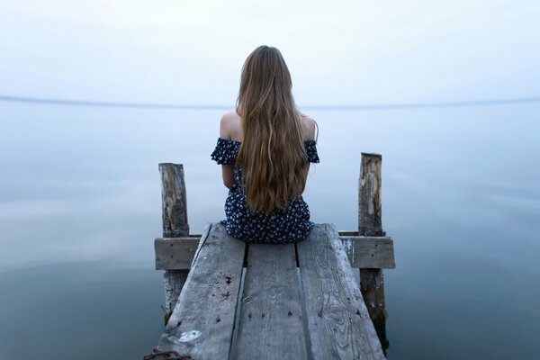 De pelo largo chica sentada junto al agua