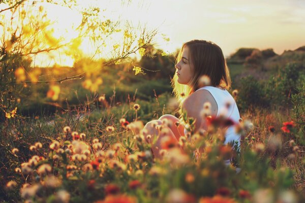 Chica en el campo en el verano en el fondo de la puesta de sol