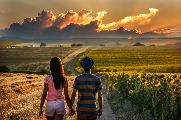 The couple walks across the field to the clouds