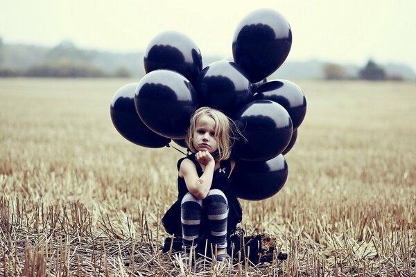 Fille avec des boules noires assis sur le terrain