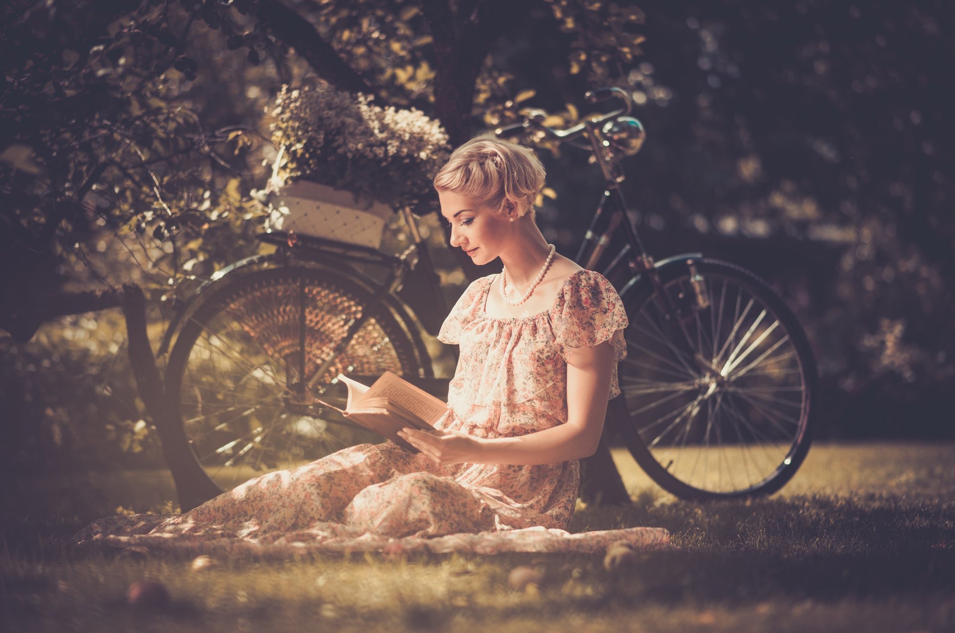 ragazza bionda vestito perline stile retrò libro legge erba bicicletta cestino fiori albero foglie natura