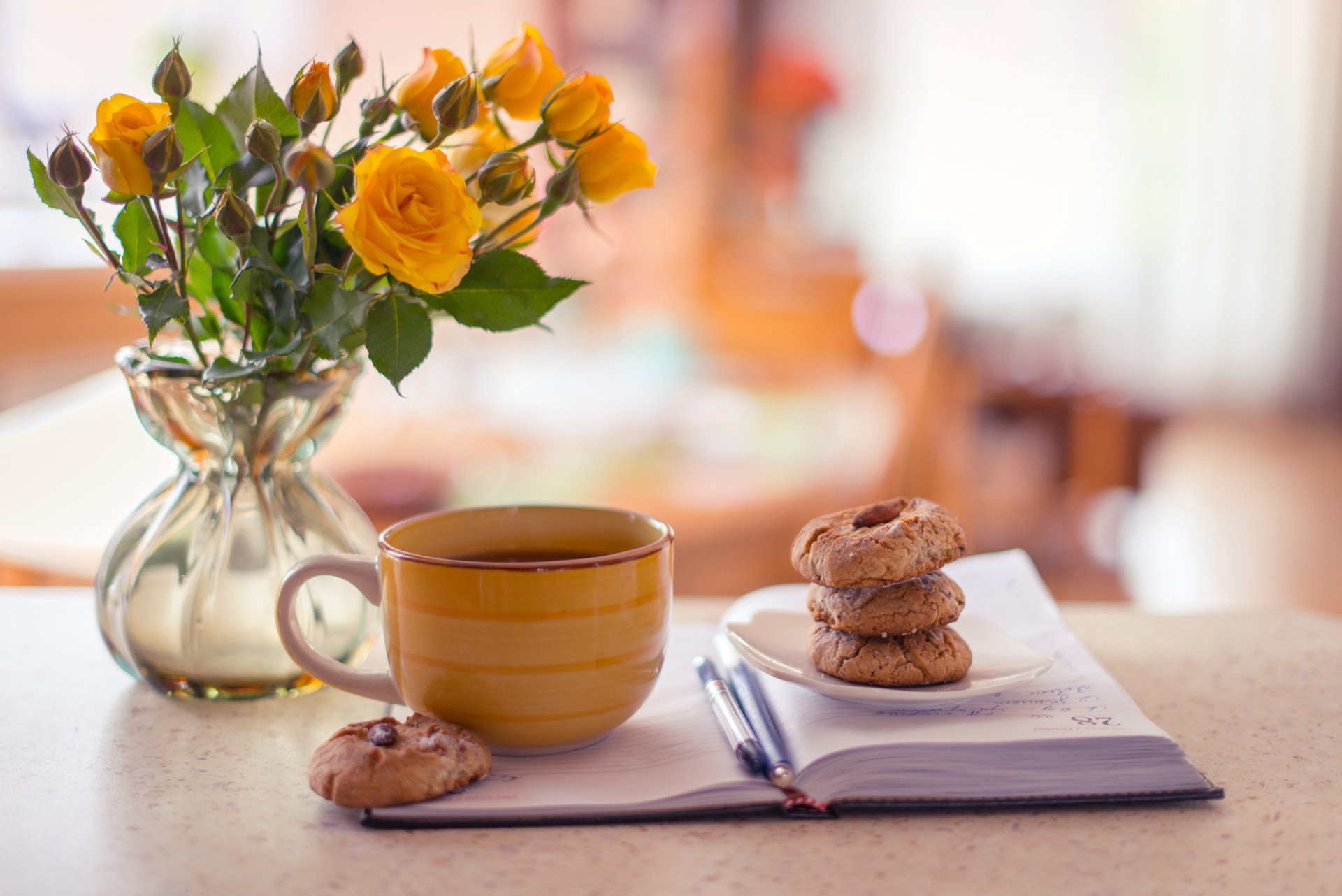 vase rosen gelb notizblock stifte tasse tee kaffee kekse gebäck