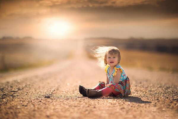 The girl is sitting on the road, the wind blows her hair