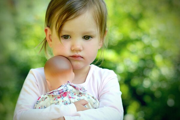 Pequeña niña triste abrazando a la muñeca