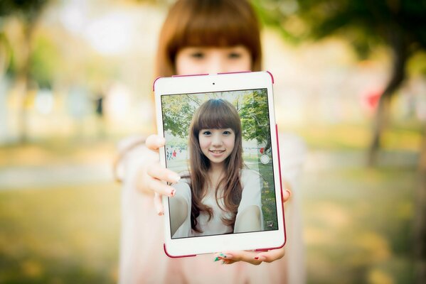 Oriental chica con la tableta de pie