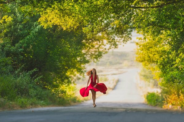 Ragazza in abito rosso cammina lungo la strada