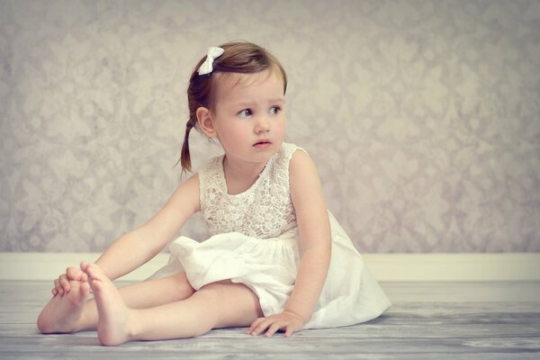 Chica en vestido blanco se sienta en el Suelo