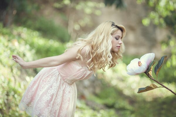 Fille dans une robe rose tendre reniflant une fleur