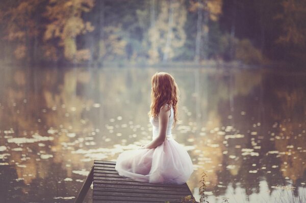 Beautiful silhouette of a red-haired girl on the background of a pond