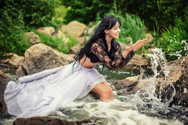 Schönes Mädchen im Fluss freut sich über Spritzer und Wasser