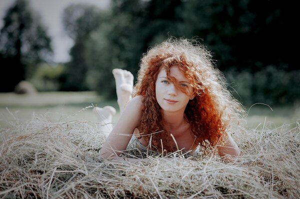 Rousse fille se trouve sur une botte de foin