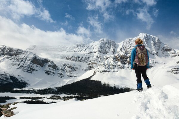 The girl is engaged in rock climbing in the mountains in winter