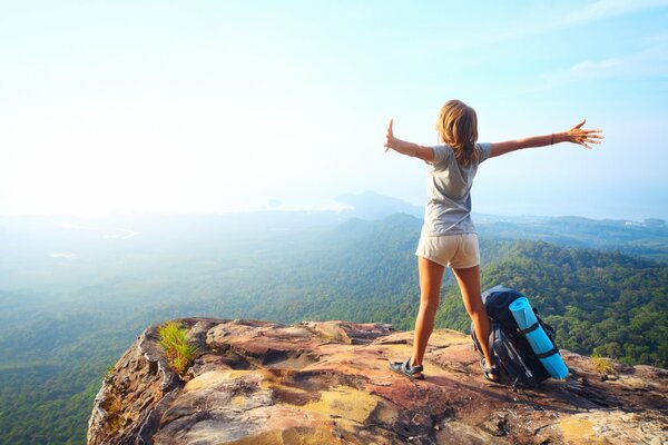 Mädchen mit Rucksack an einer Klippe in den Bergen