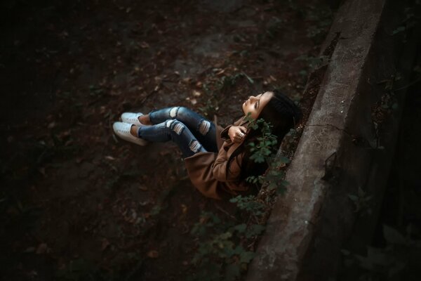 Ragazza in jeans si siede a terra