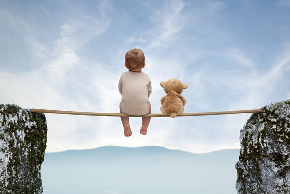 A kid with a teddy bear toy is sitting over a precipice