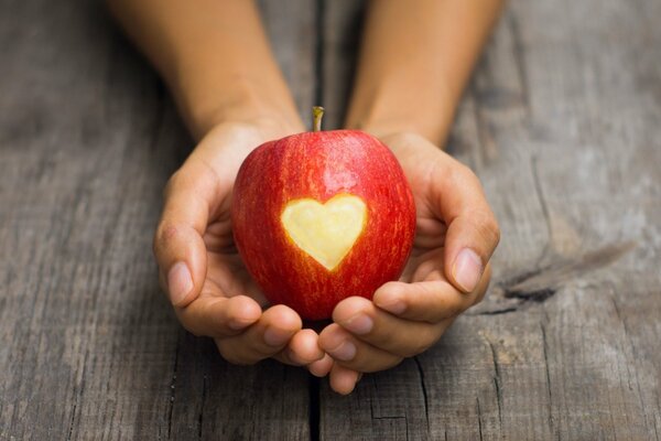 An apple with a carved heart in his hands