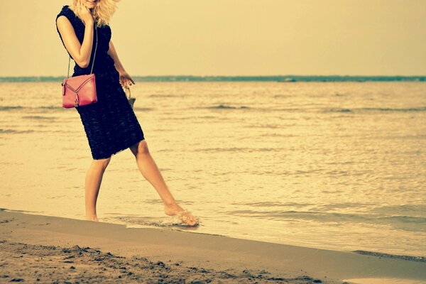 Paseo de una chica rubia en la arena del mar