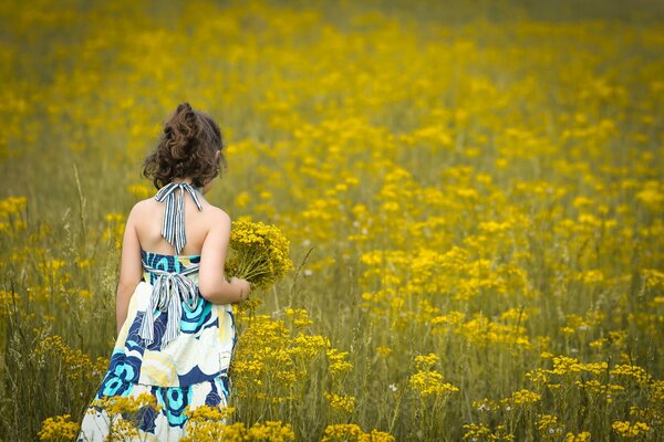 A girl in a light dress with a bouquet of flowers among flowers