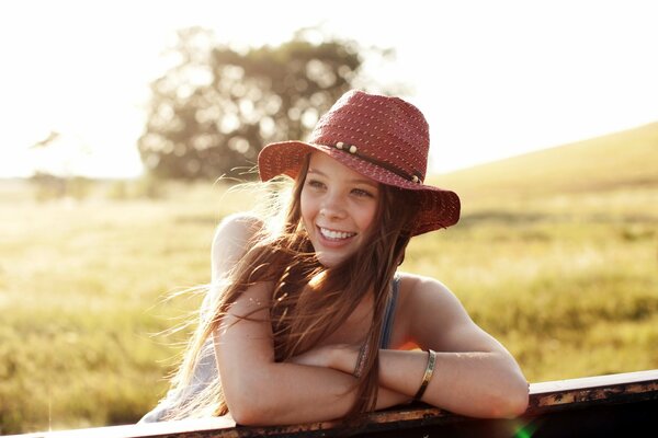 A girl in a hat smiles on a summer day