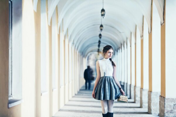 The girl with the books looks thoughtfully away