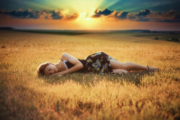 A girl in a dress is sleeping on the field