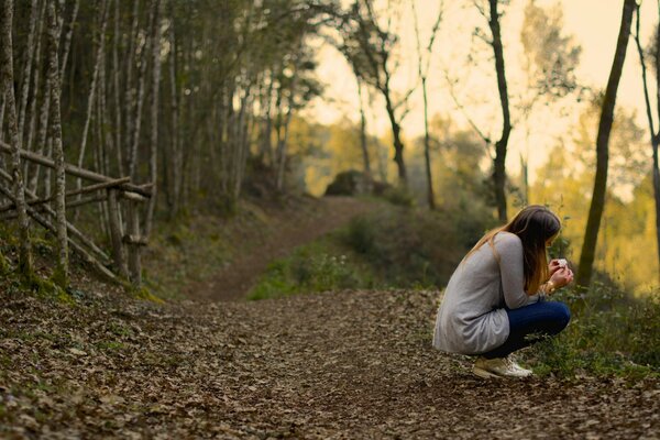 La ragazza si siede sul sentiero della foresta