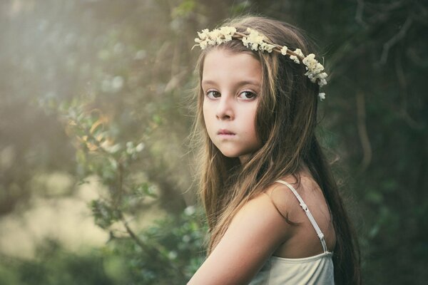 Umore triste e sguardo in una ragazza su uno sfondo widescreen. Corona di fiori sulla testa di una ragazza