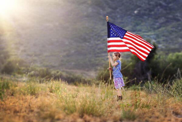 A little girl in a field with an American flag