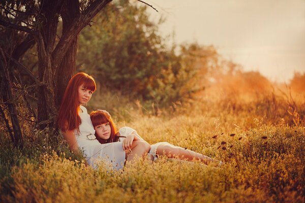 Mom and daughter are like twins under a tree in nature