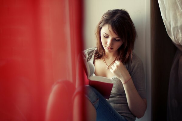 La niña Xenia Lee un libro en la ventana