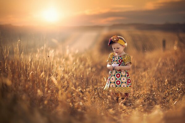 Una niña con un vestido estampado admira las espiguillas