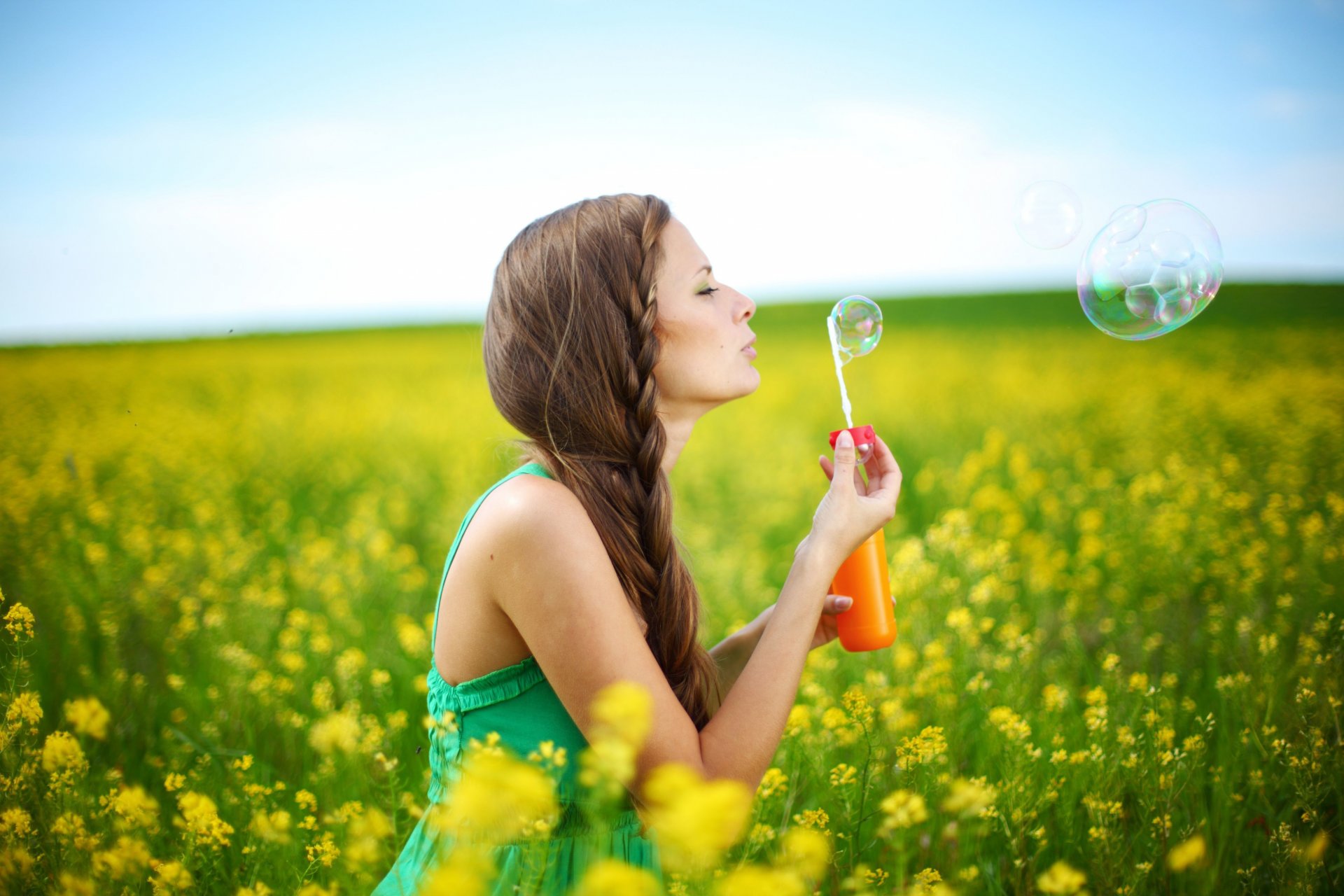 stati d animo ragazza bruna codino acconciatura estate vestito bolle di sapone piante natura fiori fiori giallo sfondo cielo donna bruna positivo gioia felicità libertà mani sorriso pianta alberi albero foglie volantini ampiamente