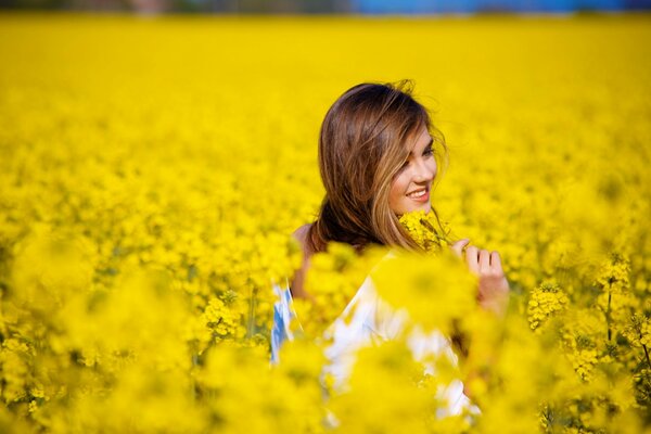 A girl smiles on a field with dandelions