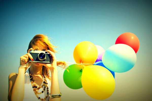 A girl with a camera and bright balloons