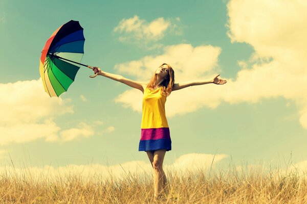 Fille dans un champ avec un parapluie multicolore