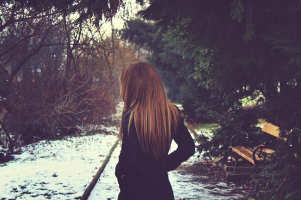 Fille aux cheveux longs près du banc en hiver