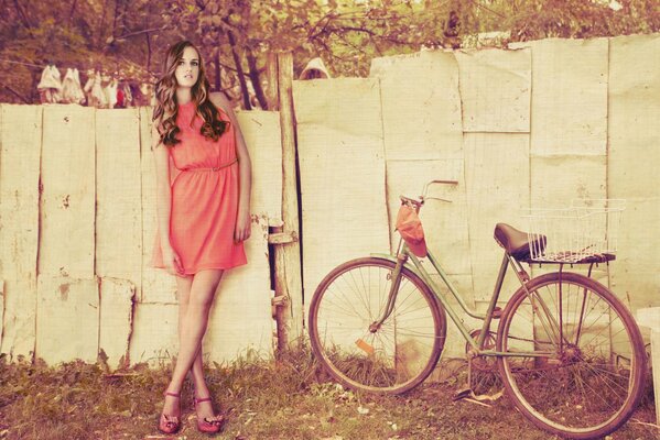 Cute girl with a bicycle on a fence background