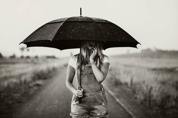 Et il pleut et une fille sur la route avec un parapluie