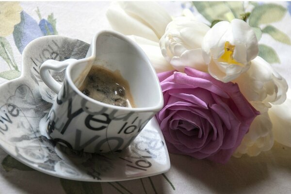 Coffee cup with a bouquet of roses on the table