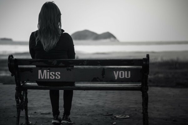 A girl is sad on a bench by the sea